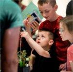 Kellen Mourer, 4, inspects a plant while exploring student projects with his family during the Groundswell Stewardship Initiative student project showcase on the Pew Grand Rapids Campus May 15.